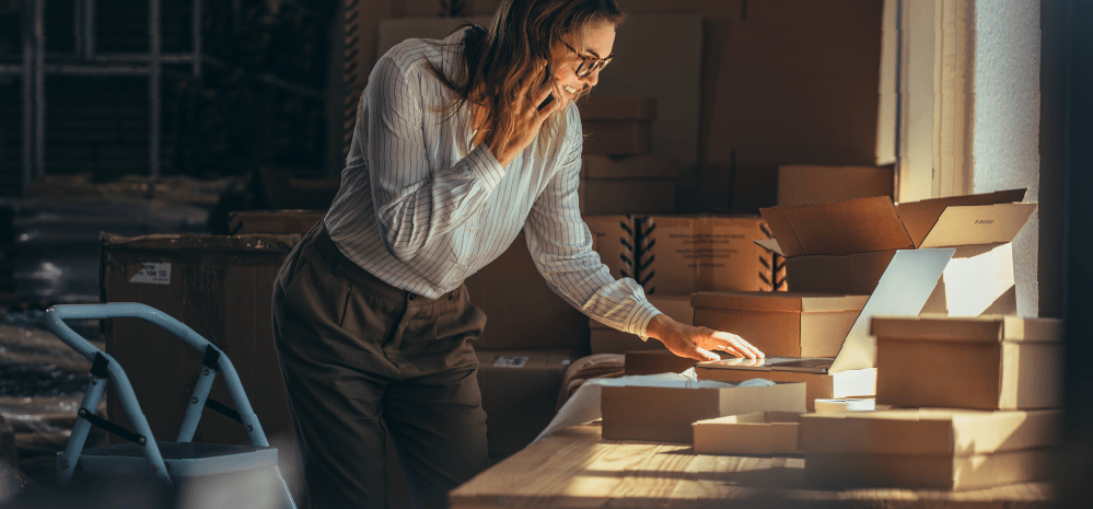 Persona revisando su computadora mientras atiende una llamada telefónica